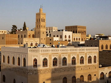 Old City of Sana'a Yemen tower houses with white geometric plasterwork and stained glass windows at golden hour, representing rich Yemeni cultural heritage