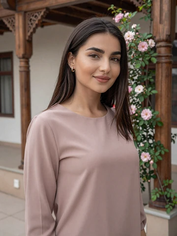 Tajik woman in elegant rose blouse standing in traditional courtyard with carved wooden pillars, representing genuine Tajik dating profiles