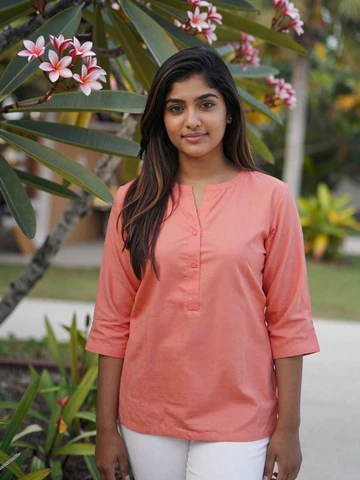 Maldivian woman in coral tunic smiling in tropical garden near Malé, representing genuine Maldivian dating profiles on Asian iDatingZone