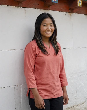 Pema, 27, Bhutanese woman from Wangdue near traditional whitewashed wall, open to cross-cultural dating